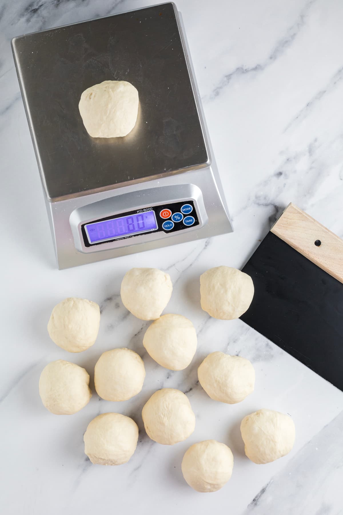 Divided sourdough bagel dough portions weighed to 75 grams each before shaping.