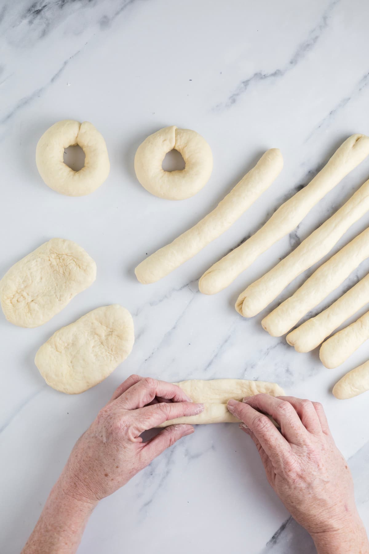 Rolling a piece of sourdough bagel dough into a rope for the rope shaping method.