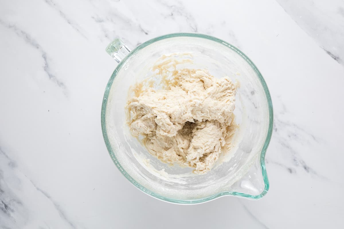 Shaggy sourdough bagel dough in a stand mixer before kneading.