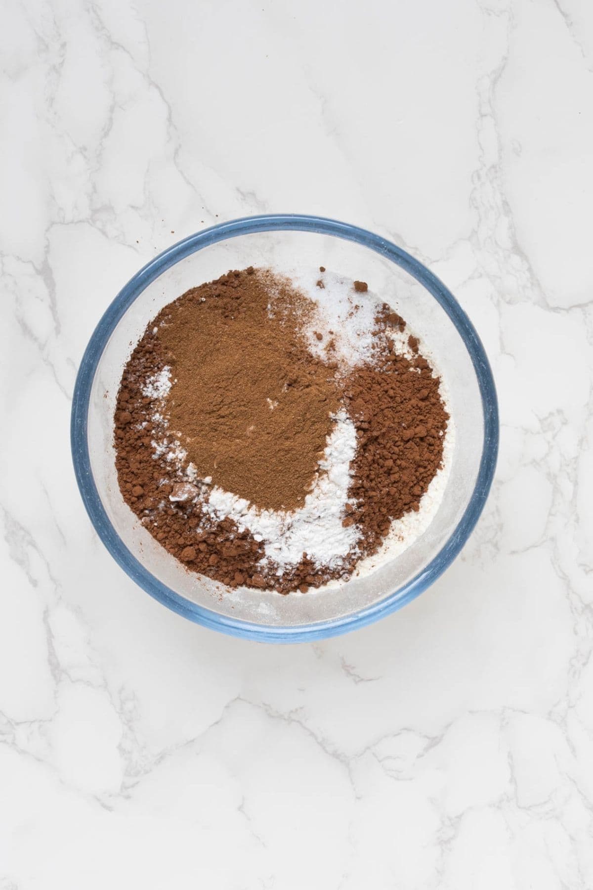 Dry ingredients in a glass mixing bowl to be combined for sourdough chocolate snickerdoodle cookies.