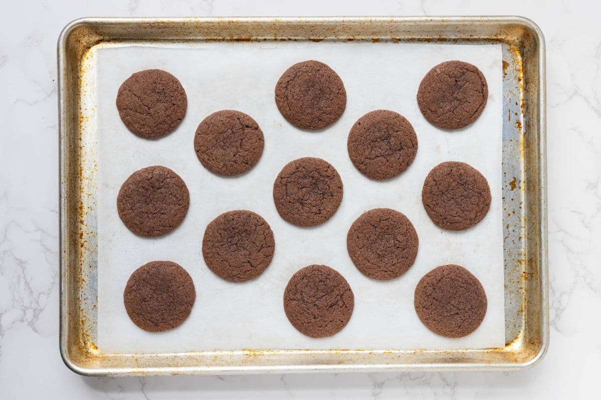 Freshly baked sourdough chocolate snickerdoodle cookies cooling on a parchment-lined baking sheet.