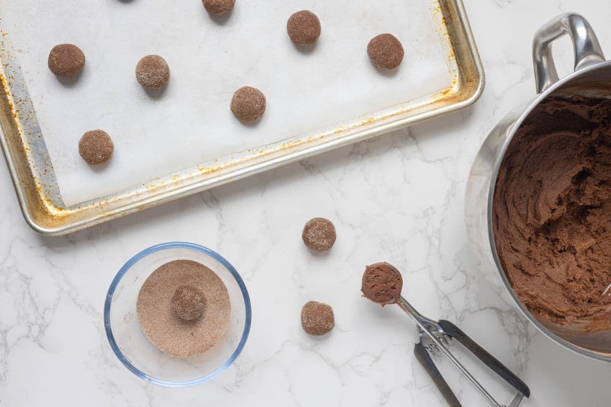 Chocolate cookie dough scooped into cinnamon sugar and rolled into balls before baking.
