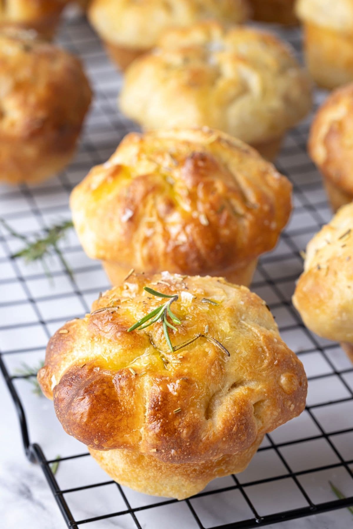 Homemade sourdough focaccia muffins cooling on a wire rack after baking.