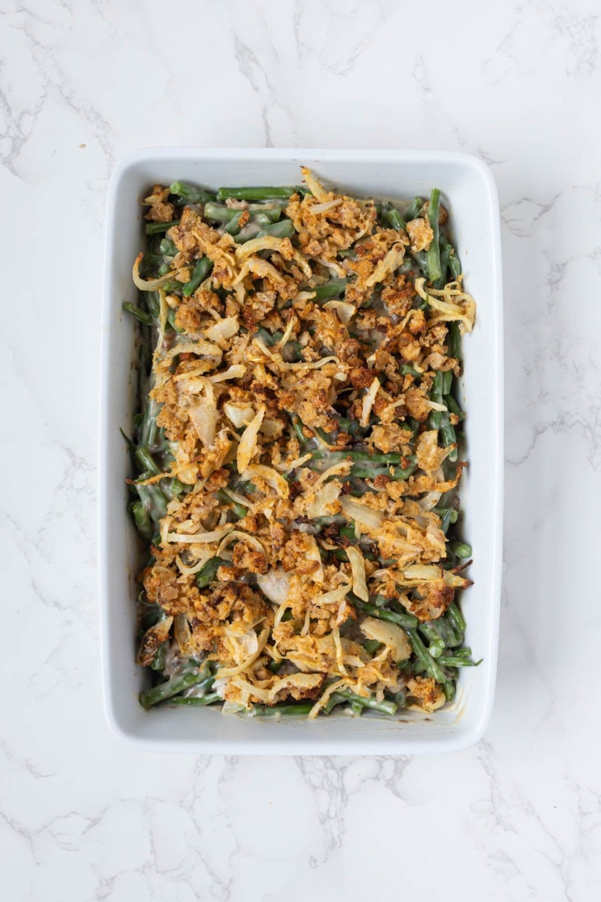 Sourdough green bean casserole assembled with mushroom sauce and onion topping before baking.