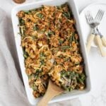 Homemade sourdough green bean casserole in a baking dish with a wooden serving spoon.