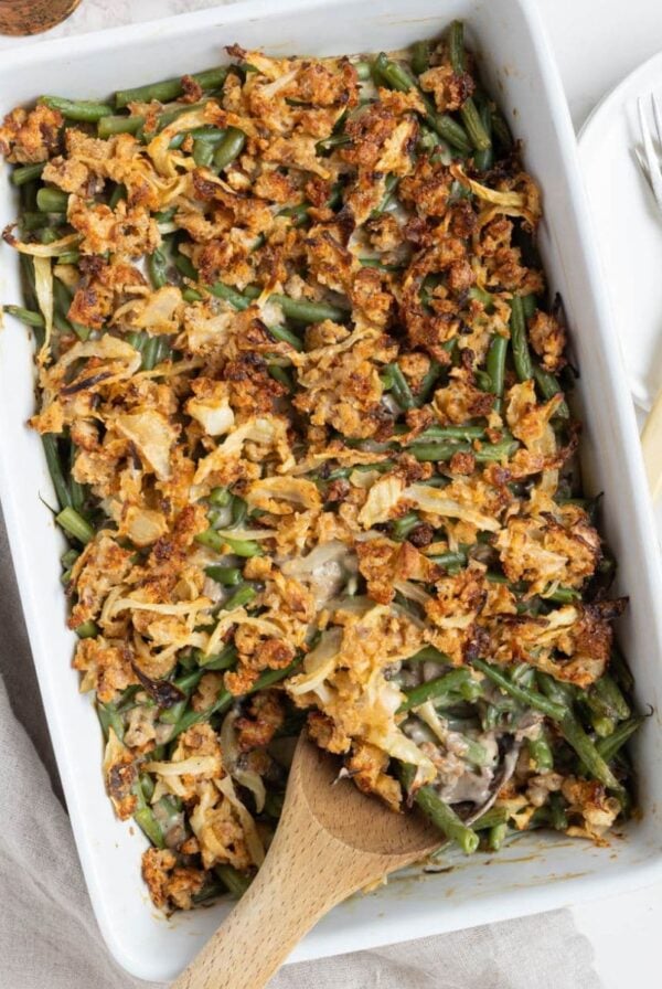 Homemade sourdough green bean casserole in a baking dish with a wooden serving spoon.