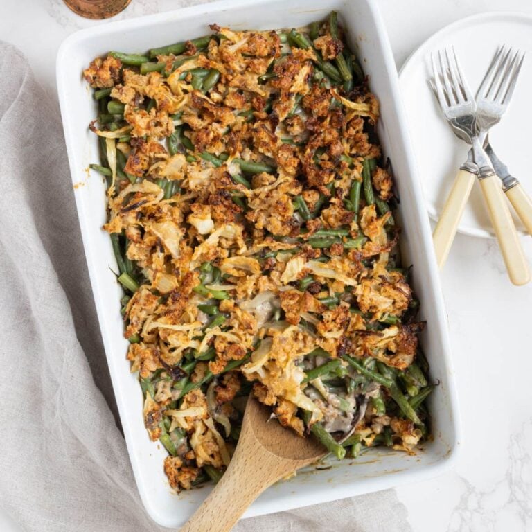 Homemade sourdough green bean casserole in a baking dish with a wooden serving spoon.