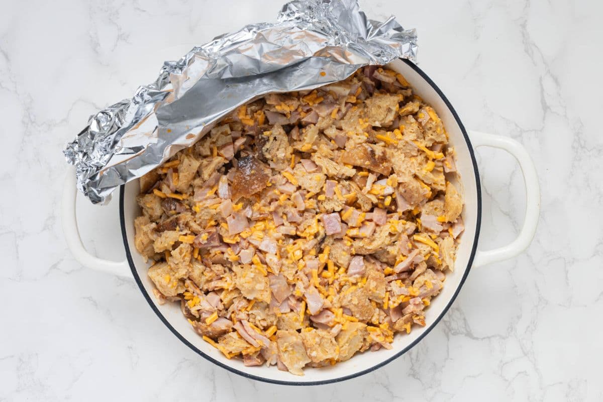Removing foil from a sourdough ham and cheese strata before baking.