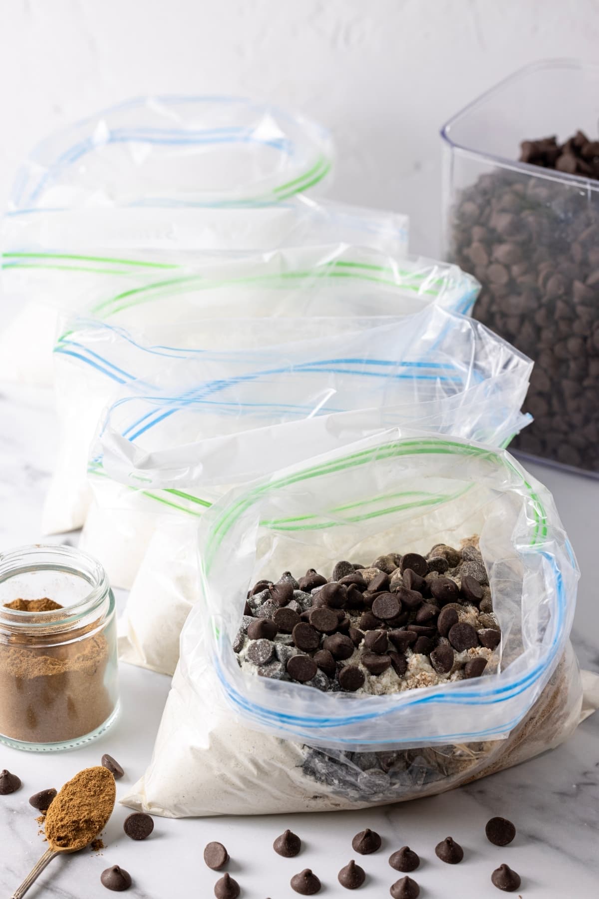 An image showing 5 resealable plastic bags filled with dry sourdough muffin mix. The one at the front has chocolate chips and cinnamon added to it.