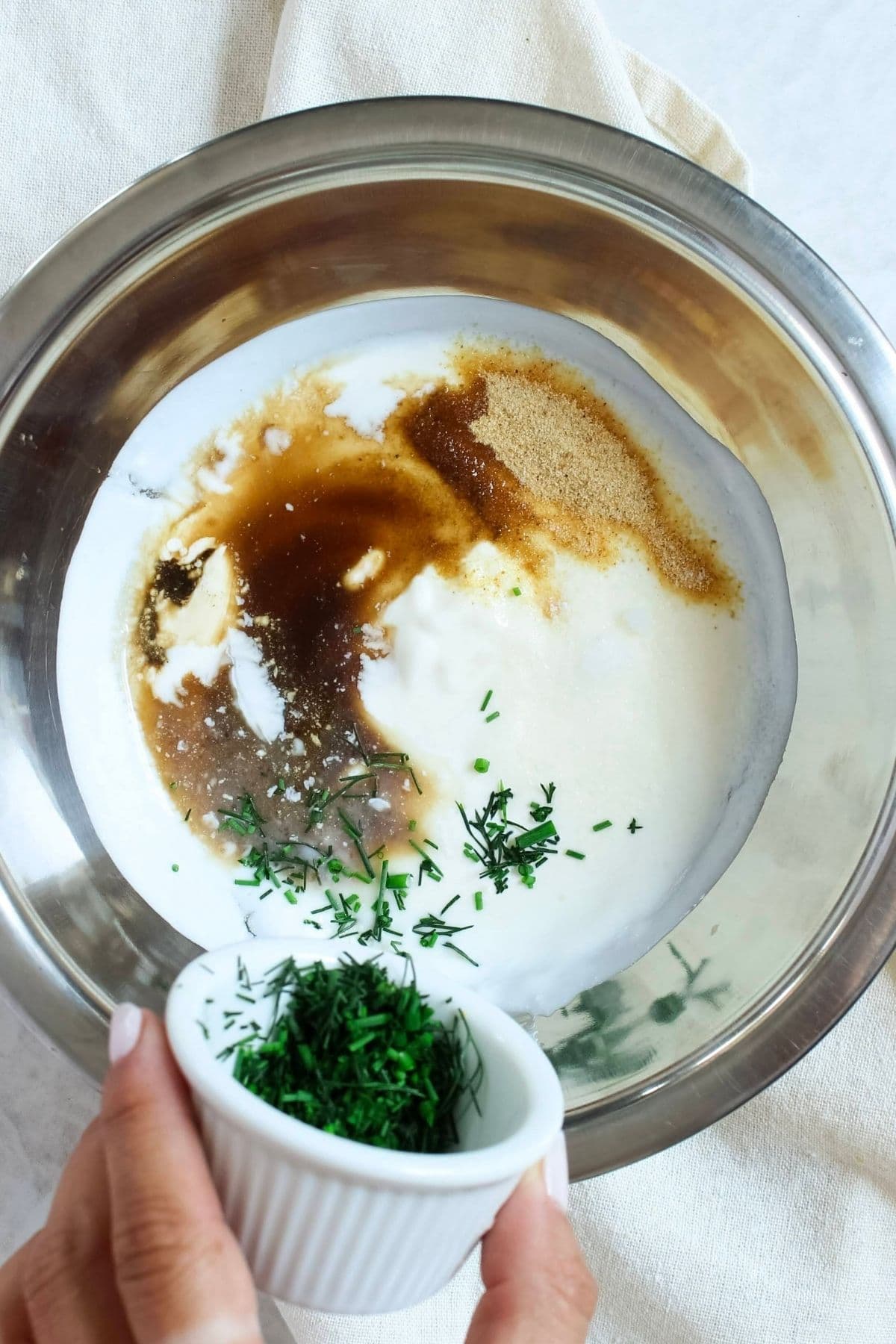 Fresh dill and chives being added to the ingredients for homemade ranch dressing.