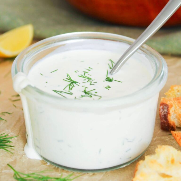Close-up of creamy homemade ranch dressing topped with fresh dill and chives.