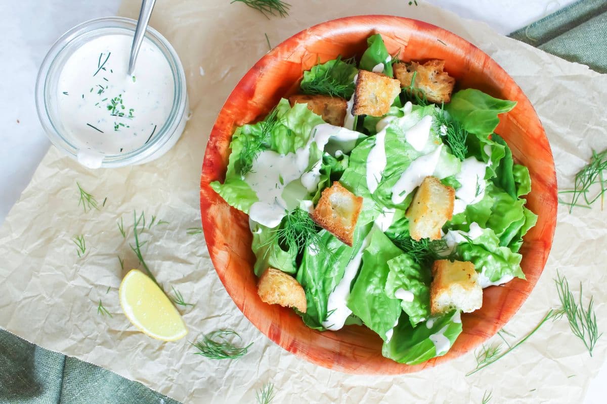 Green salad with sourdough croutons, fresh dill and homemade ranch dressing drizzled over the top.