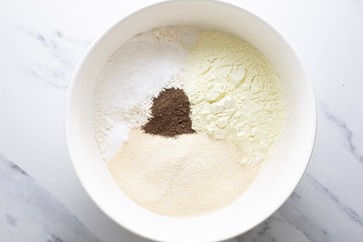 A large white bowl filled with dry ingredients for making sourdough muffin mix.