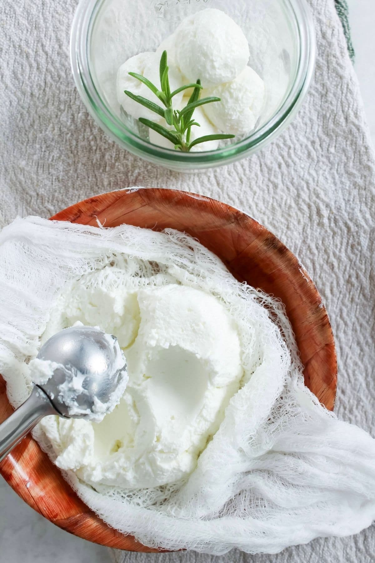 Scooping out homemade labneh from a cheesecloth and adding to a glass jar.