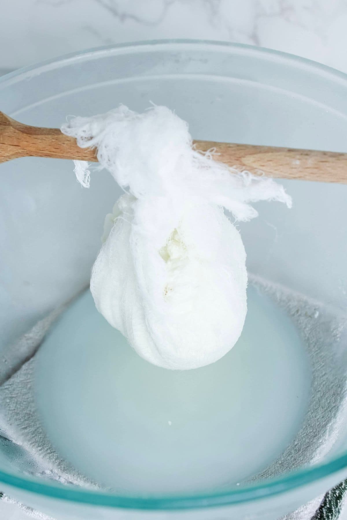 Strained yogurt in a cheesecloth hanging over a bowl to make labneh.