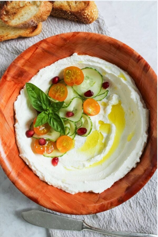 Homemade labneh in a bowl for serving with a knife for spreading onto toasted sourdough bread.