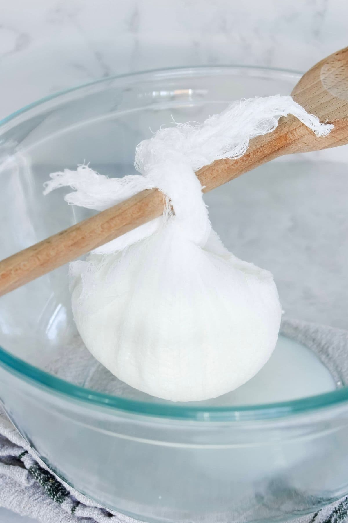 Close up of making labneh by hanging the yogurt inside a cheesecloth over a glass bowl.