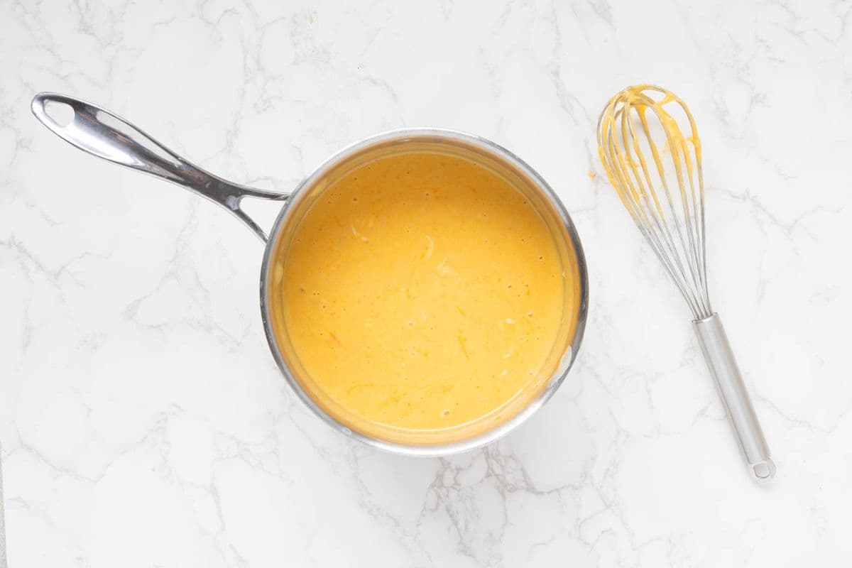 A saucepan with a rich cheese sauce that has been whisked together.