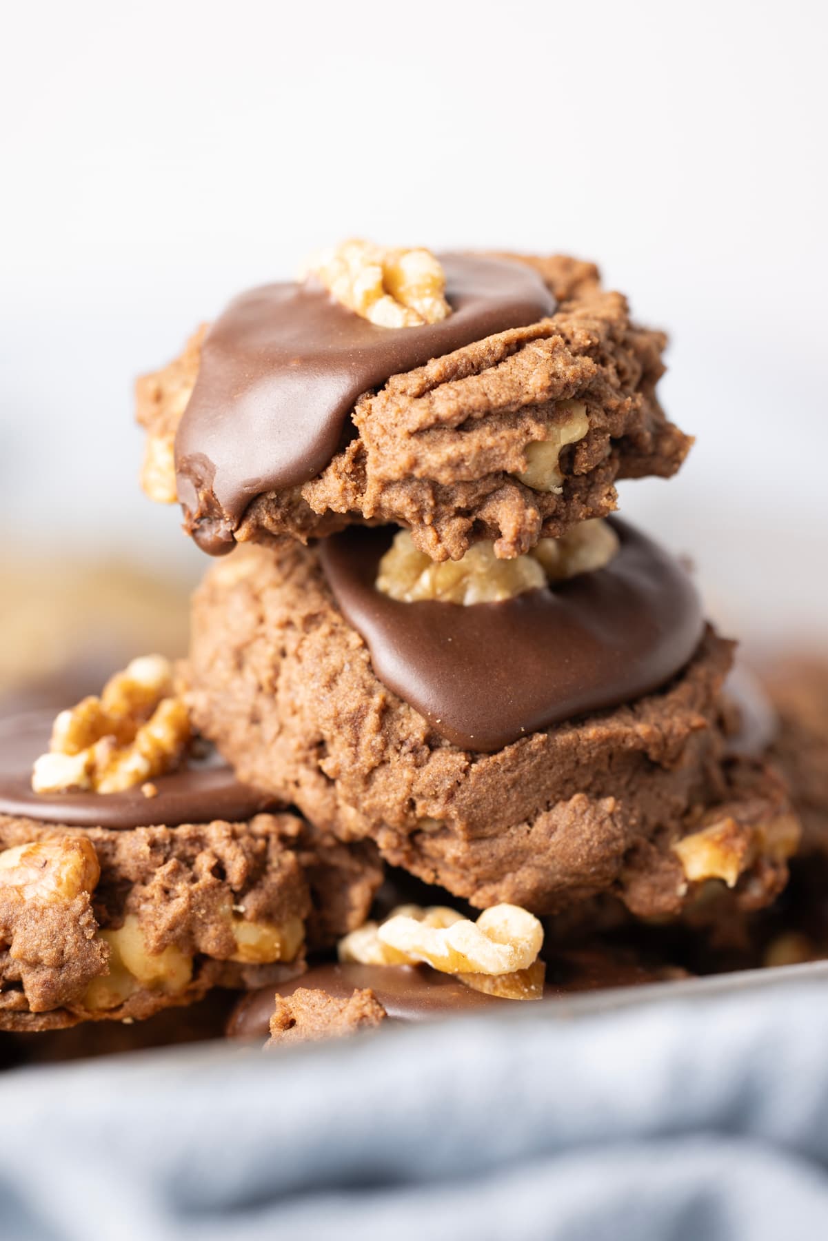Close-up of sourdough chocolate walnut cookies topped with chocolate icing and walnut halves.