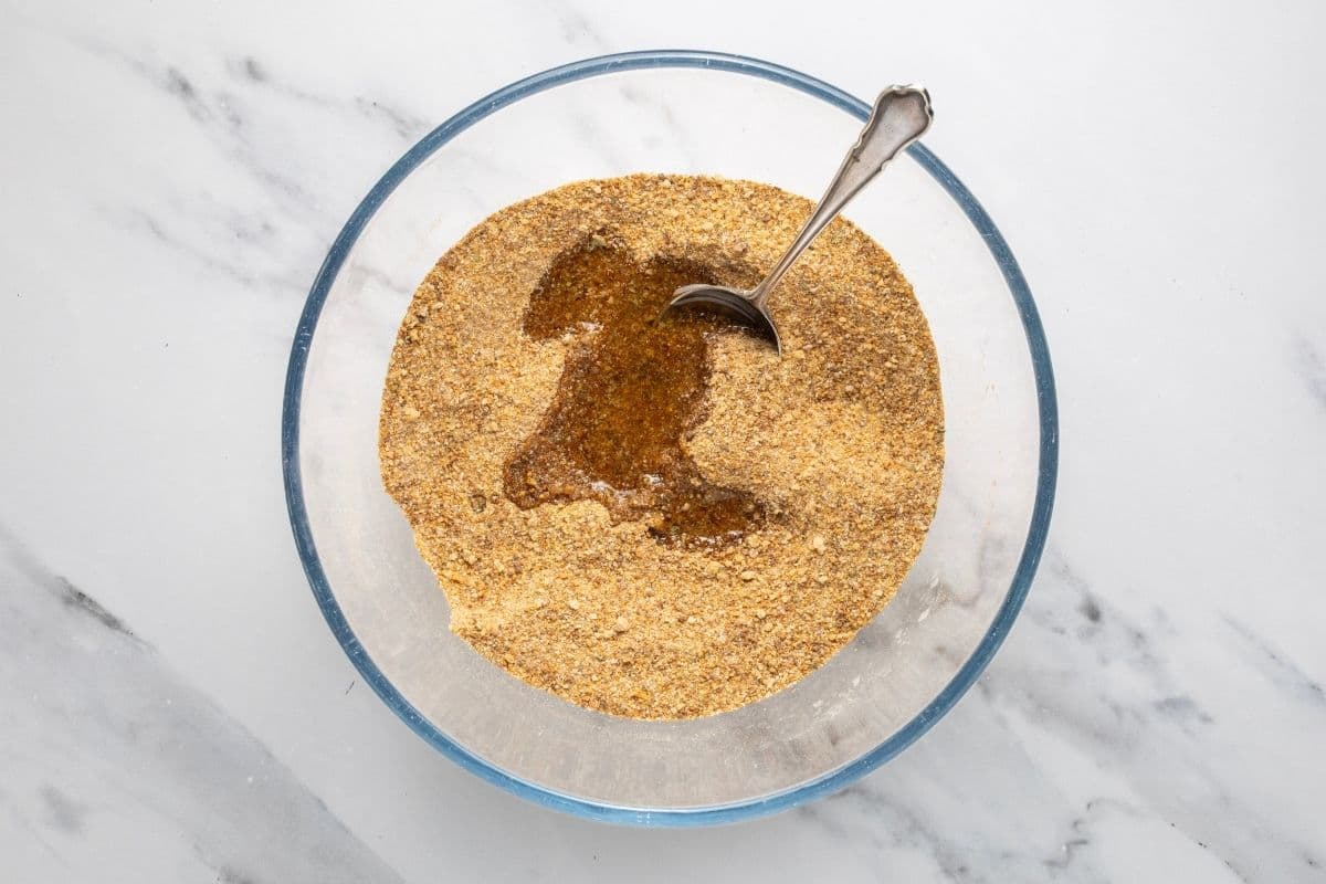 A glass bowl containing sourdough shake and bake dry ingredients with the vegetable oil sitting on top.