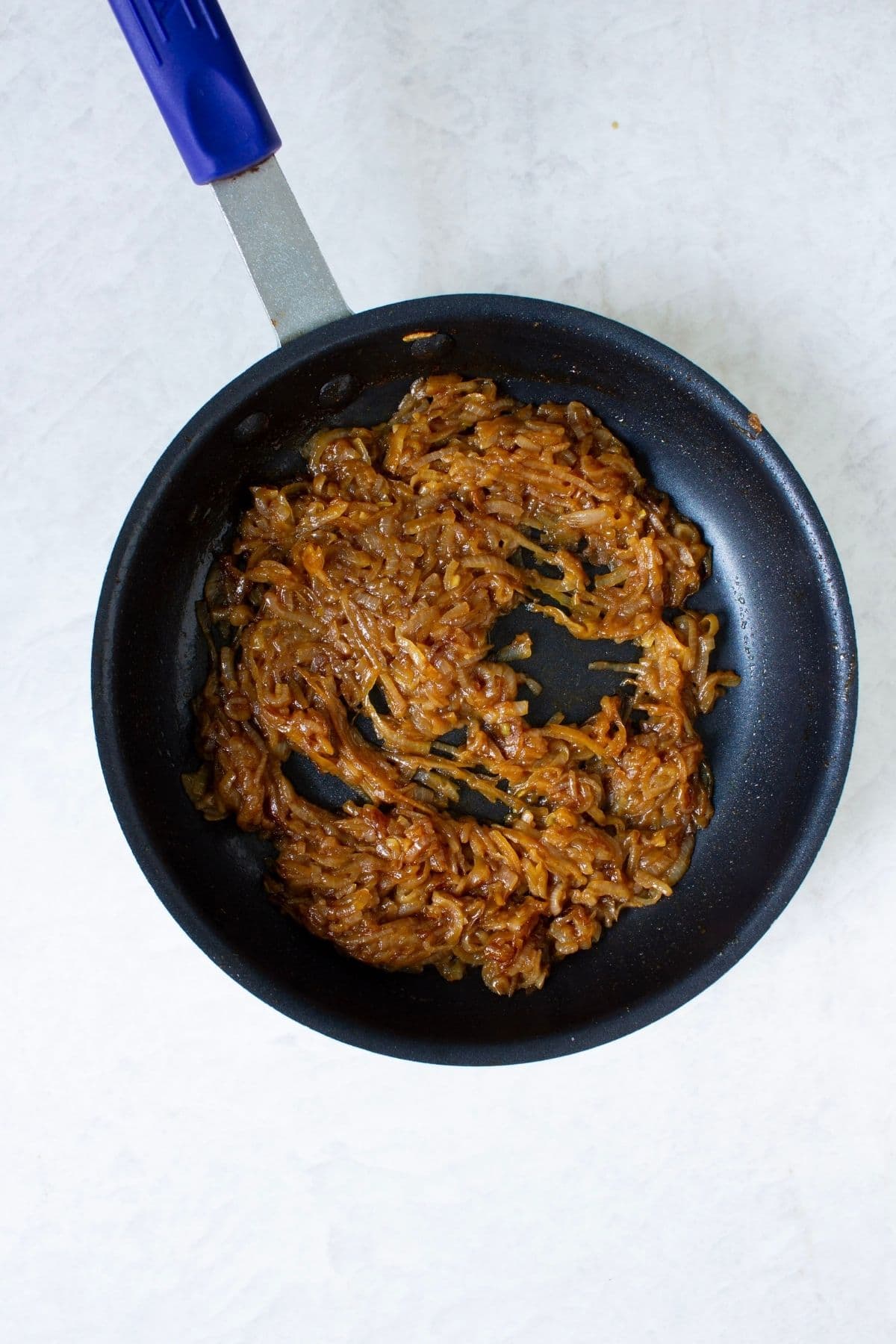 Deep golden brown caramelized onions cooked in a skillet for homemade French onion dip.