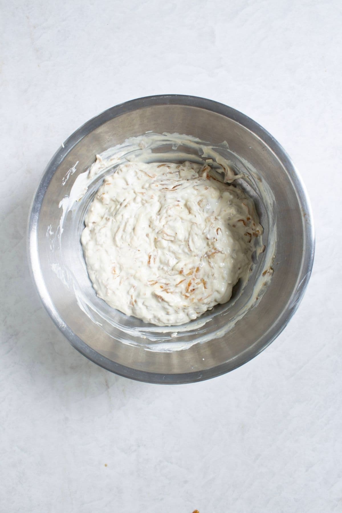 Creamy French onion dip mixed with caramelized onions in a mixing bowl.