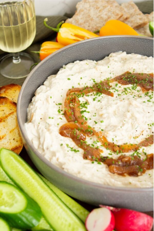Caramelized French onion dip topped with caramelized onions and fresh chives, served with cucumber, radishes, peppers, and toasted sourdough bread.