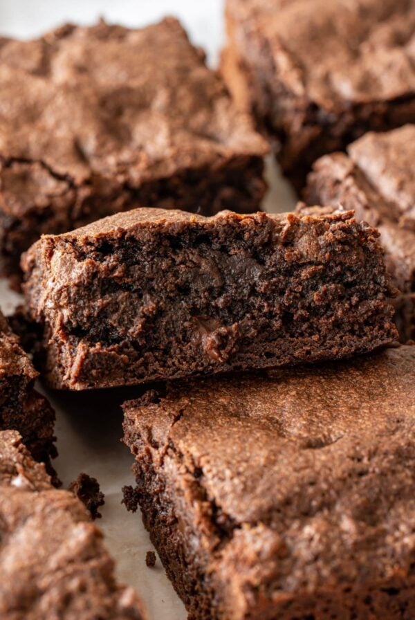 A vertical image showing a close up of a square of sourdough brownie. You can see the rich, fudgy center and the crackly, meringue tops.