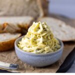 A small grey butter filled with jalapeno honey butter that has been piped into the dish. There is a loaf of sourdough bread in the background.