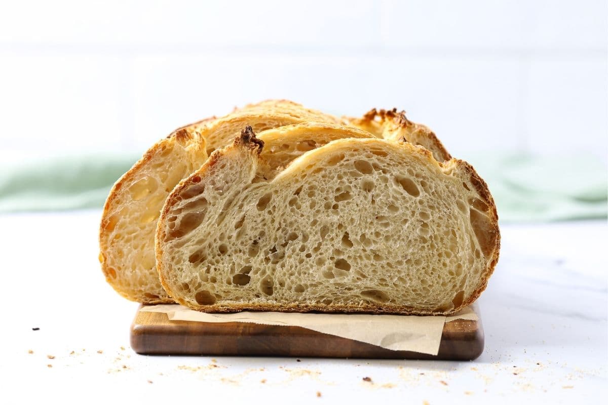 A front view of a loaf of sourdough bread that has been sliced open so you can see the light, airy crumb inside.