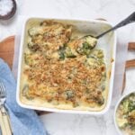 Creamy sourdough broccoli casserole topped with golden, crunchy breadcrumbs, with a spoonful being served from the baking dish.