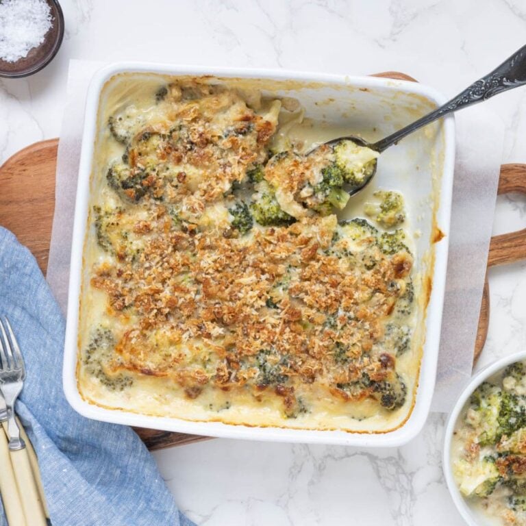 Creamy sourdough broccoli casserole topped with golden, crunchy breadcrumbs, with a spoonful being served from the baking dish.