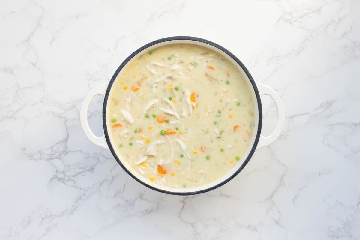 A photo of the finished sourdough chicken pot pie soup in a large cream heavy based pot.