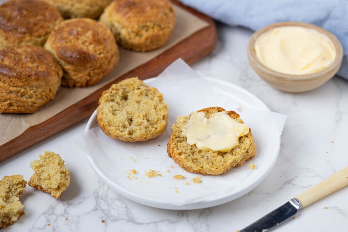An image showing a sourdough cornbread biscuit split open and spread with butter.
