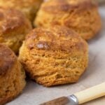 A close up image of a batch of sourdough cornbread biscuits showing the flaky layers and golden brown out layer.
