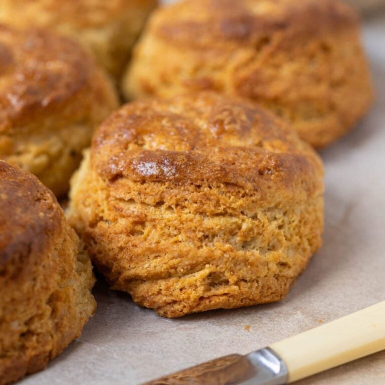 A close up image of a batch of sourdough cornbread biscuits showing the flaky layers and golden brown out layer.