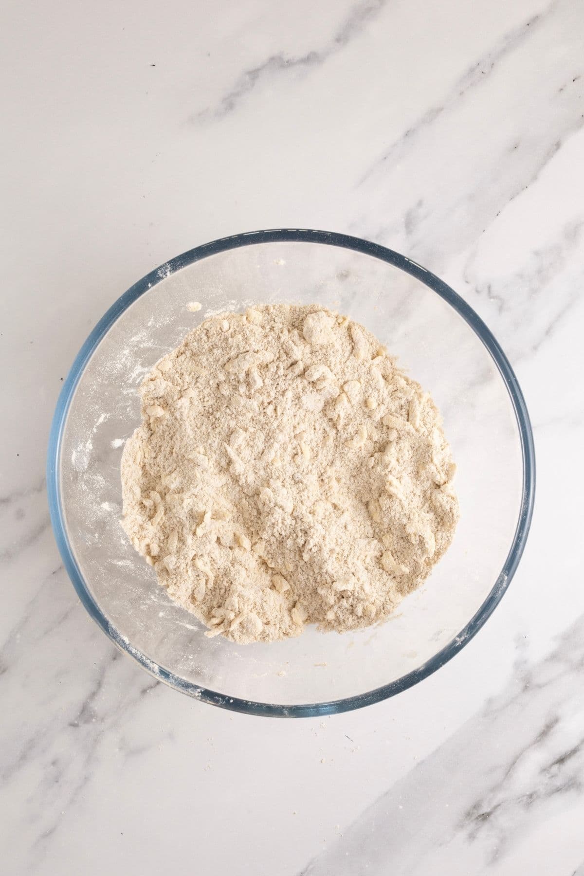 A glass bowl showing what the dry ingredients should look like with the butter rubbed in.