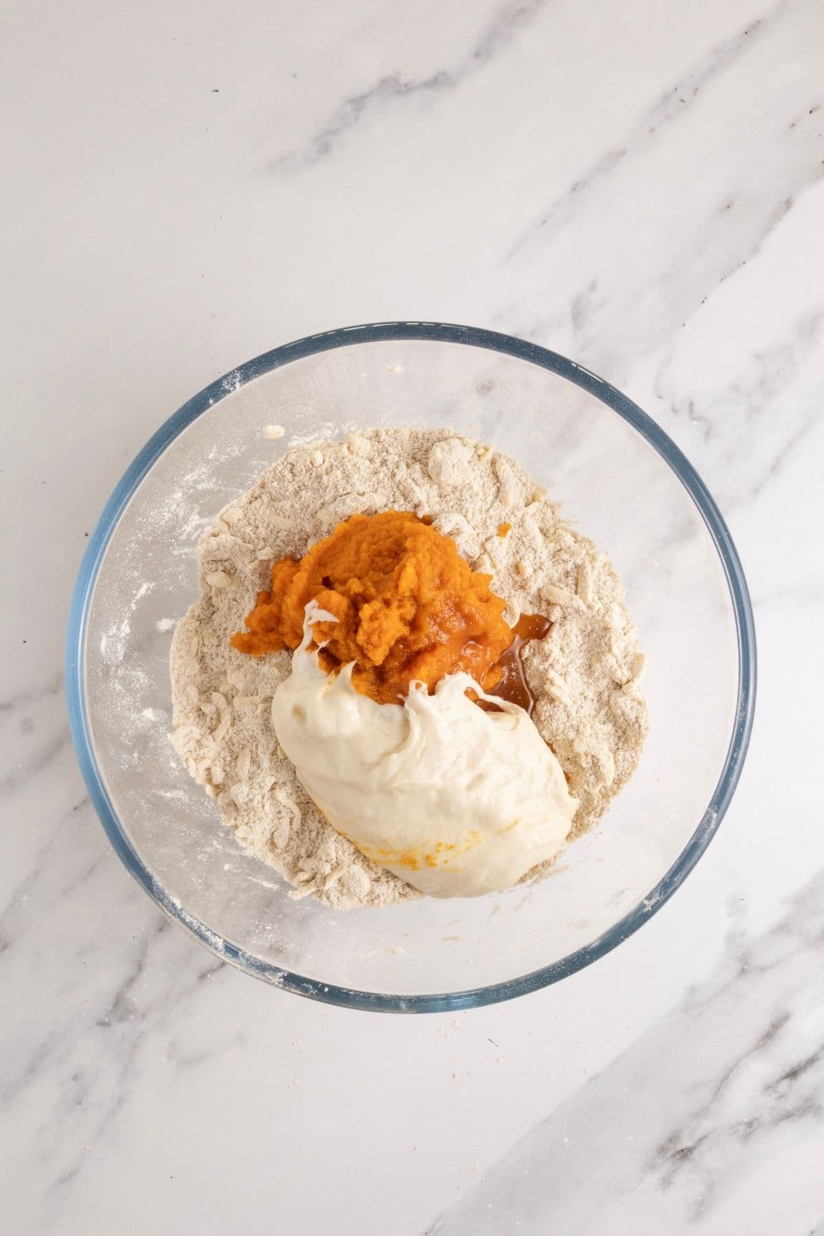A glass bowl showing the dry ingredients with the wet ingredients tipped on top.