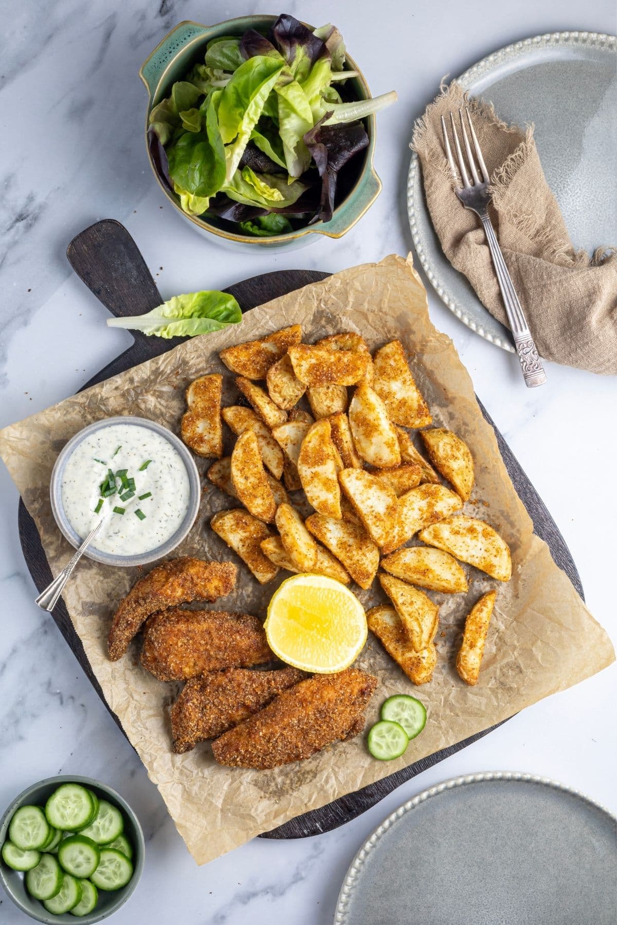 An image taken from above showing a platter filled with chicken tenders and potato wedges made with sourdough shake and bake.
