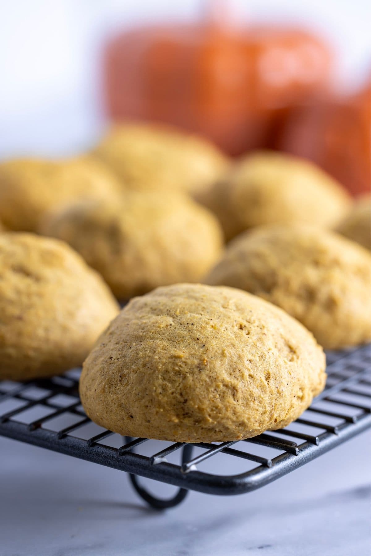 A horizontal image showing the freshly baked sourdough pumpkin spice cookies cooling on a wire cooling rack.