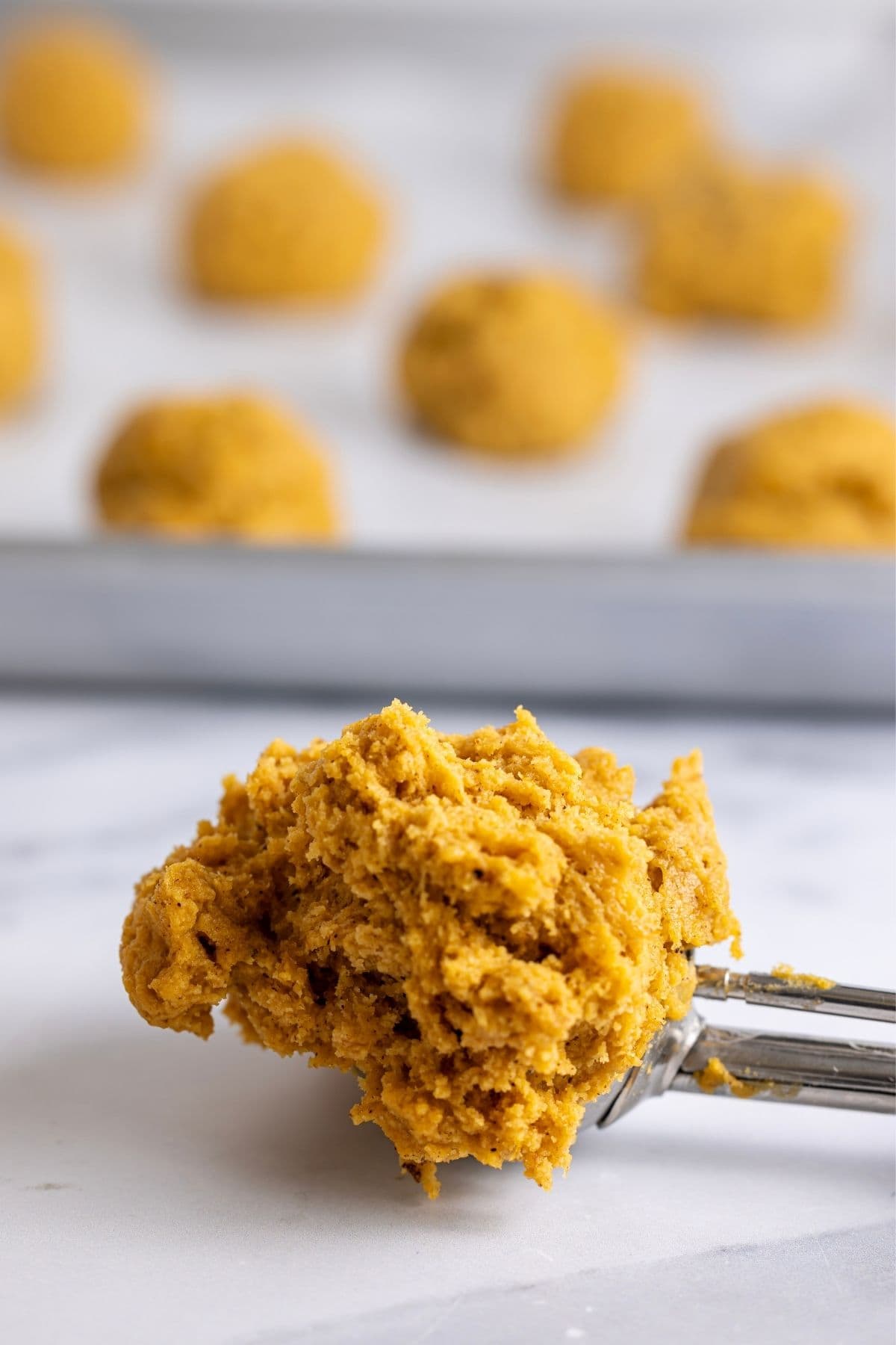 A close up image of soft sourdough pumpkin spice cookie dough scooped on a 2 tablespoon cookie scoop.