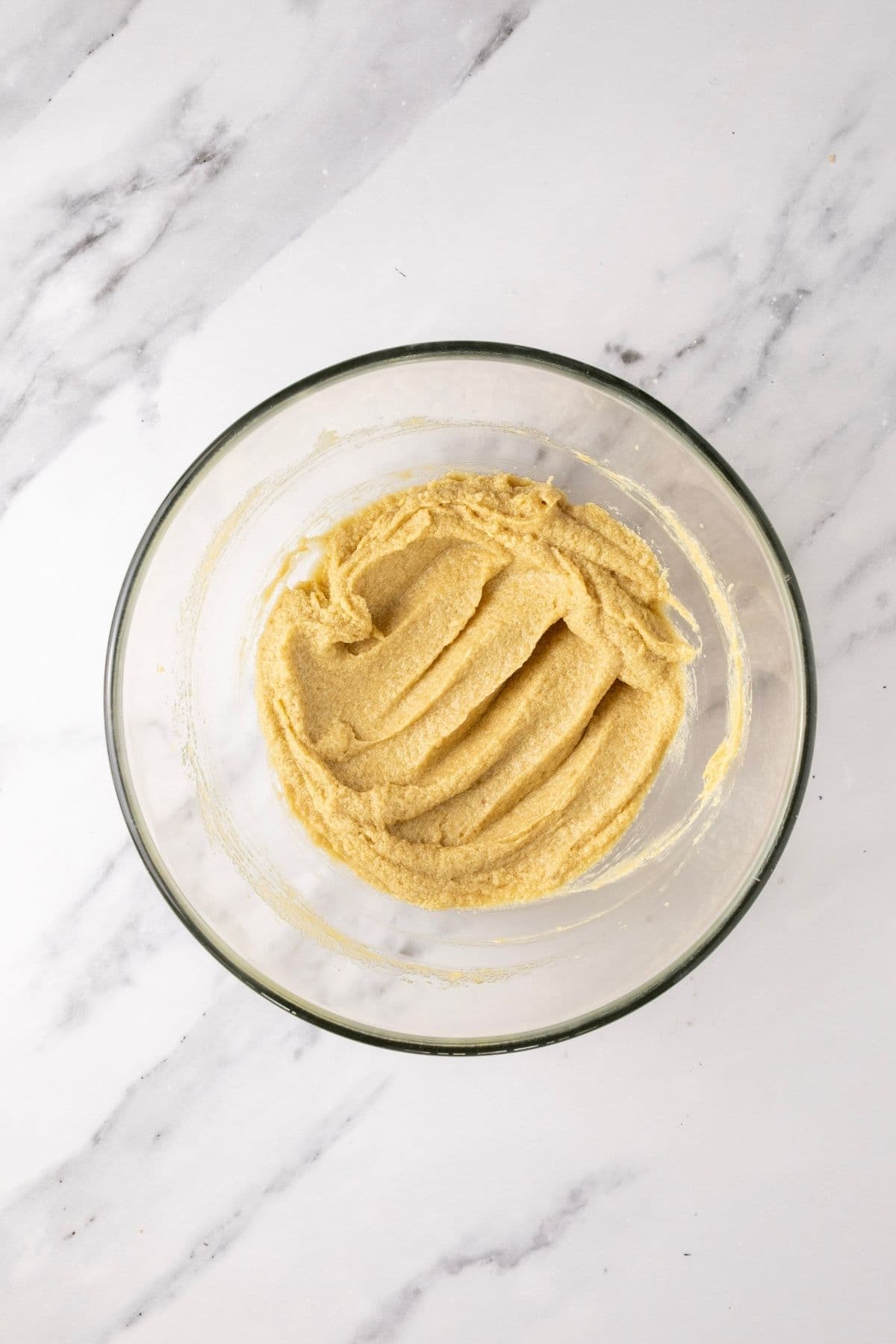 A glass bowl containing the wet ingredients, whipped until light and fluffy.